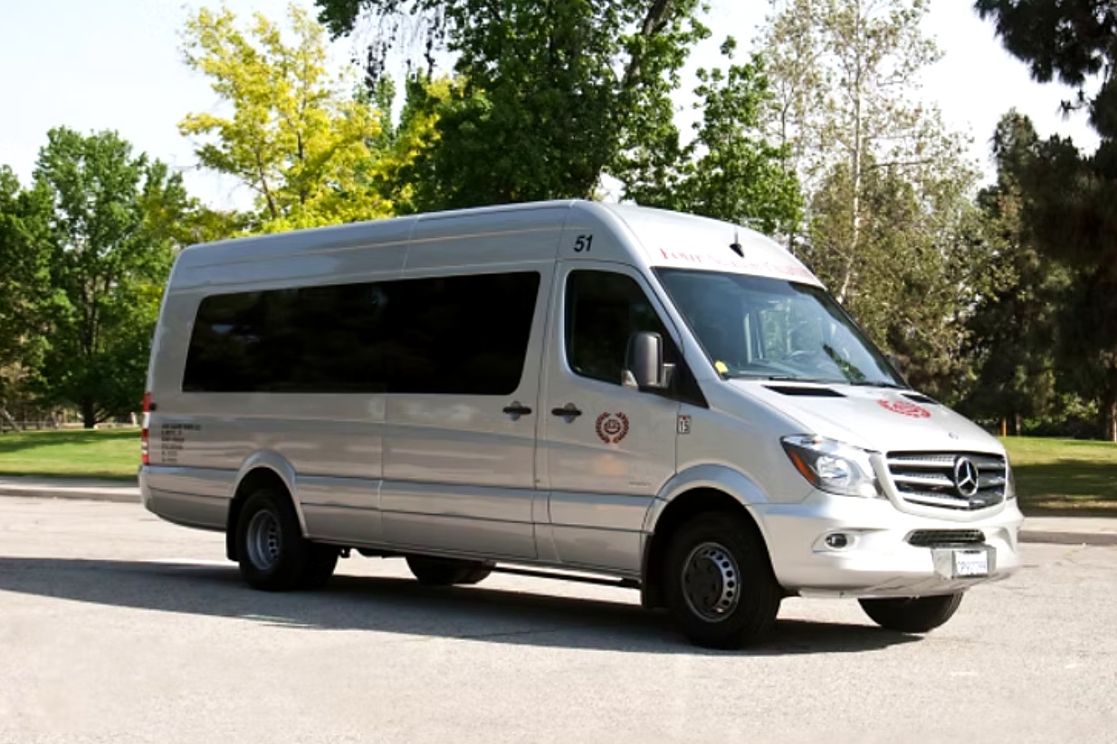 Side profile of the silver Four Season Travel Mercedes-Benz Sprinter parked beside a park