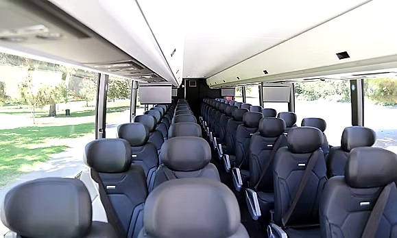 Wide interior view of a Four Season Travel full-size coach with reclining seat rows and overhead luggage racks
