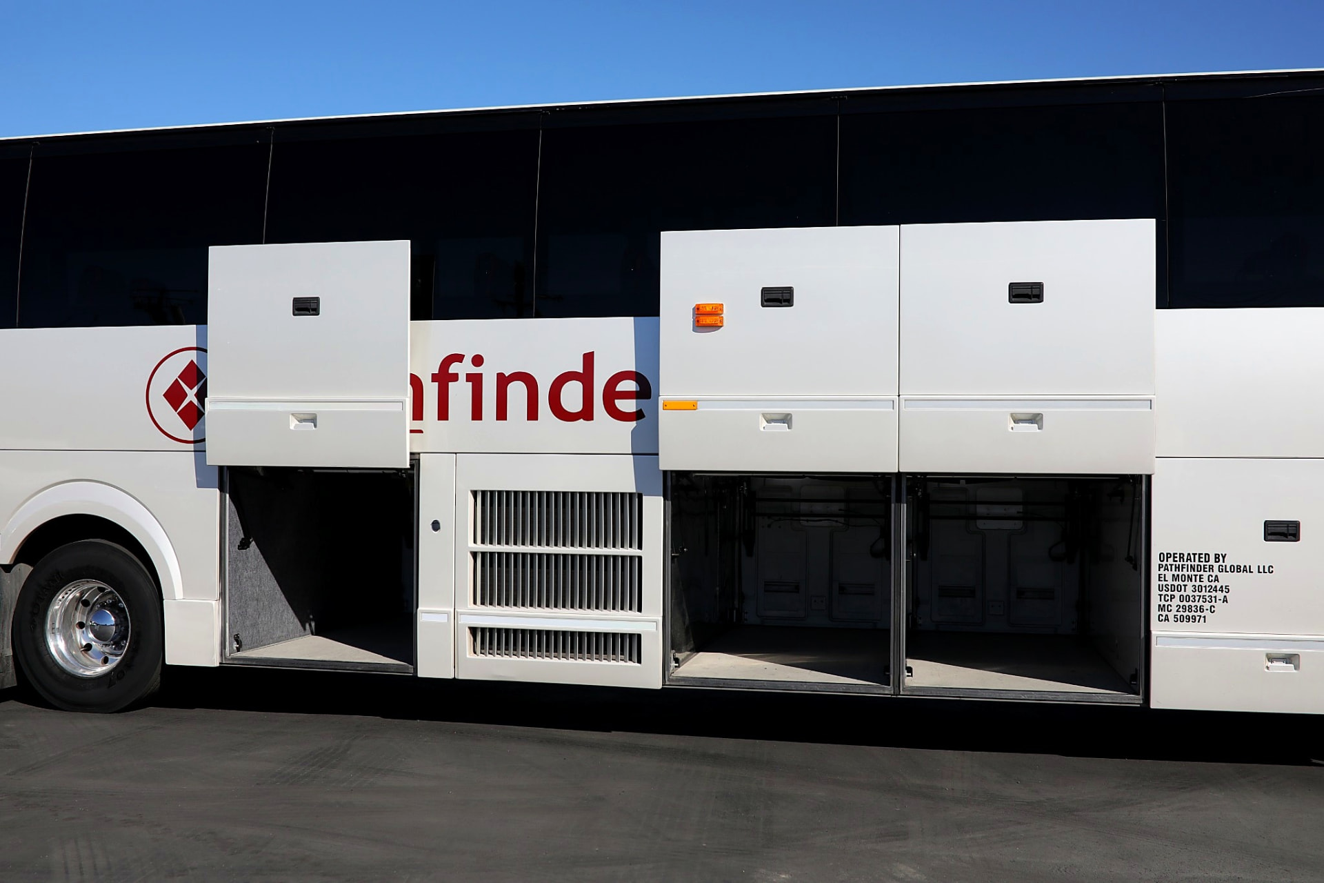 Under-floor luggage compartments open along the side of a Four Season Travel motorcoach